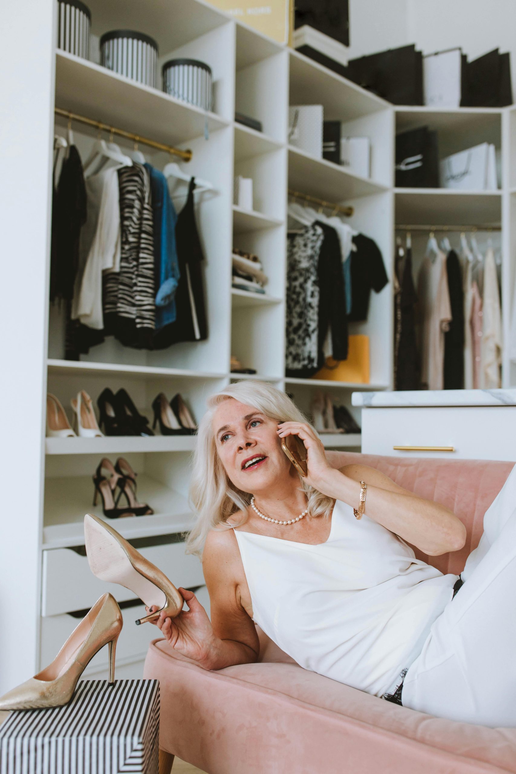 Une retraitée papotant avec son amie au téléphone au milieu de son dressing
